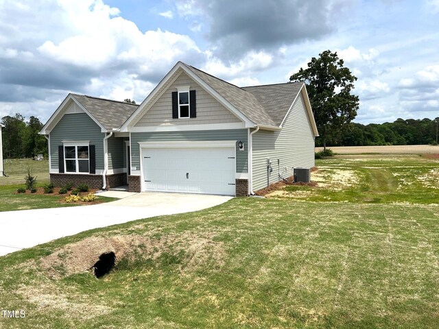 craftsman-style home with driveway, roof with shingles, cooling unit, and a front lawn