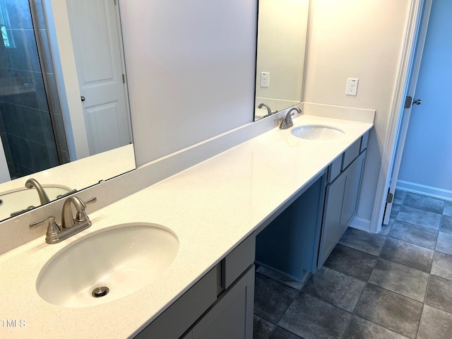 bathroom featuring a tile shower, double vanity, and a sink