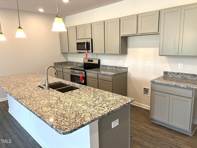 kitchen featuring dark wood finished floors, gray cabinets, light stone counters, appliances with stainless steel finishes, and a sink