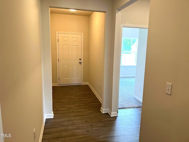 hall with dark wood finished floors, baseboards, and visible vents