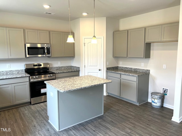 kitchen featuring light stone counters, stainless steel appliances, gray cabinets, and hanging light fixtures