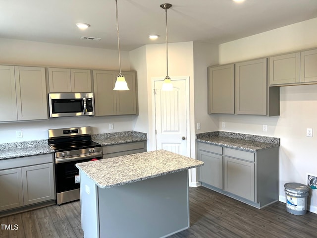 kitchen featuring stainless steel appliances, light stone countertops, gray cabinetry, and decorative light fixtures