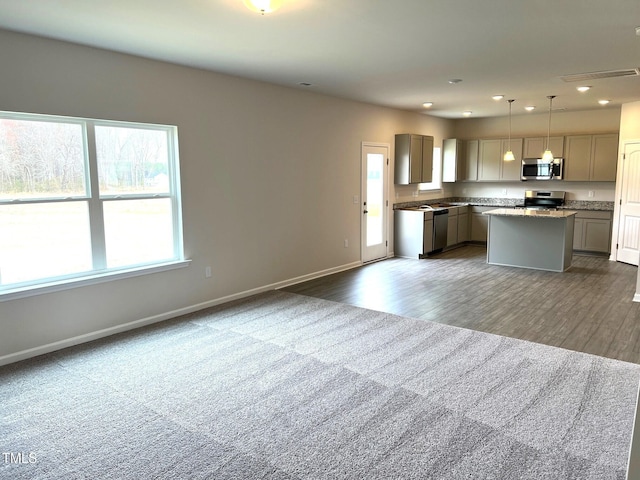 kitchen with appliances with stainless steel finishes, decorative light fixtures, gray cabinets, and a kitchen island