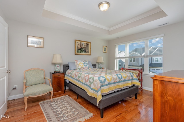 bedroom featuring a raised ceiling, wood-type flooring, and ornamental molding