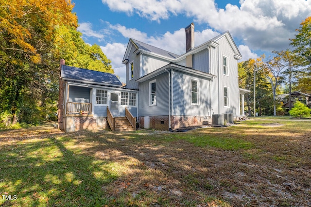 rear view of house featuring a lawn and central AC unit