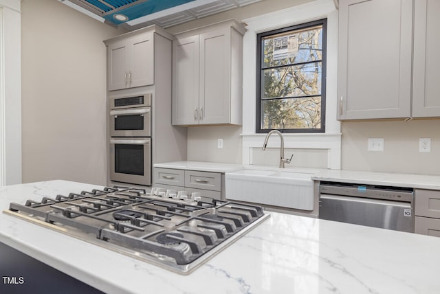 kitchen with light stone counters, appliances with stainless steel finishes, sink, and gray cabinets