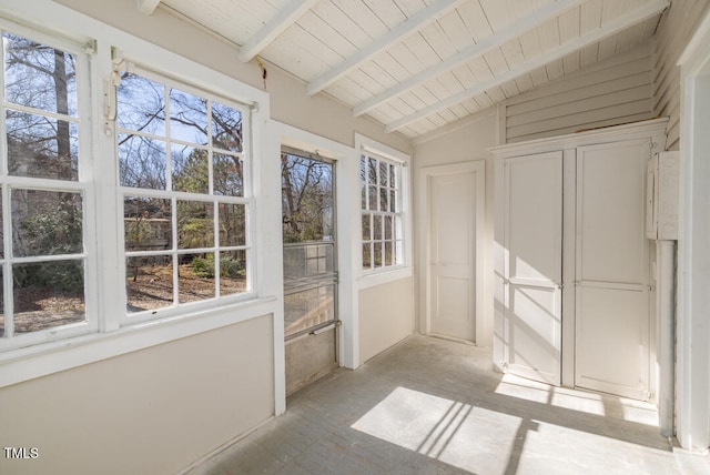 unfurnished sunroom with vaulted ceiling with beams