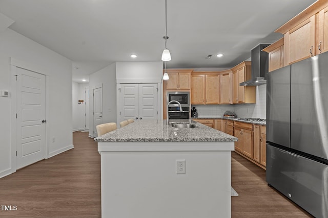 kitchen with stainless steel appliances, dark hardwood / wood-style flooring, wall chimney exhaust hood, an island with sink, and decorative light fixtures