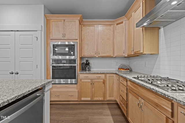 kitchen with tasteful backsplash, stainless steel appliances, dark hardwood / wood-style floors, light stone countertops, and wall chimney exhaust hood