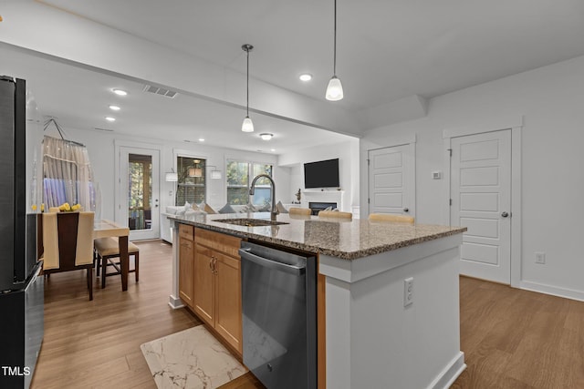 kitchen featuring light hardwood / wood-style floors, sink, an island with sink, appliances with stainless steel finishes, and decorative light fixtures