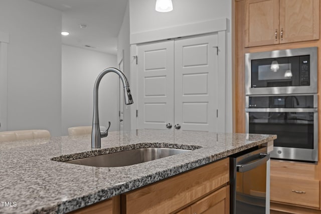 kitchen featuring appliances with stainless steel finishes, sink, and light stone countertops