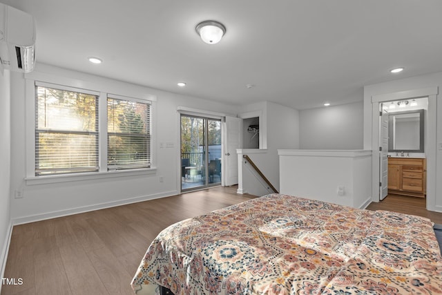 bedroom with access to outside, connected bathroom, sink, a wall mounted air conditioner, and dark wood-type flooring