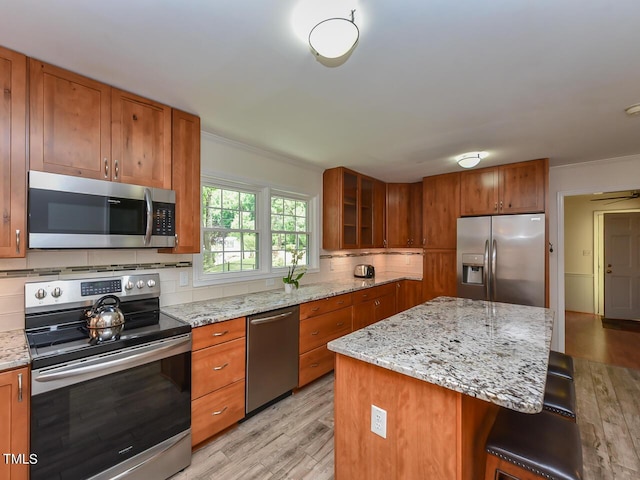 178 Paceville Rd, Selma, NC 27576 - kitchen featuring stainless steel appliances, brown cabinets, light wood-style floors, tasteful backsplash, and crown molding