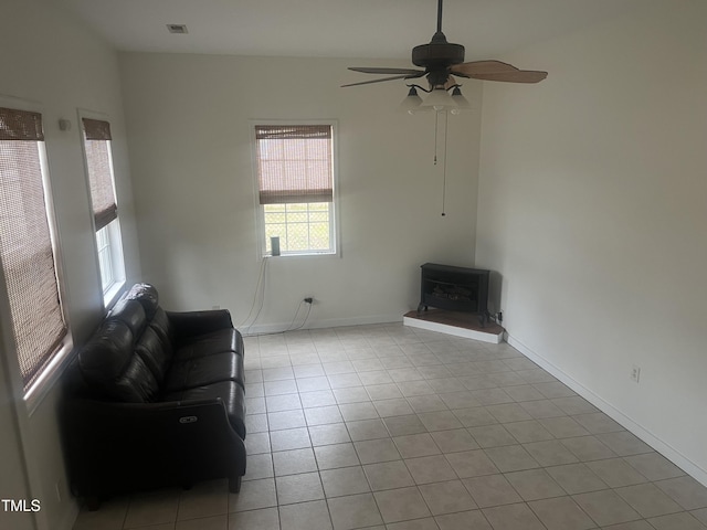 178 Paceville Rd, Selma, NC 27576 - unfurnished living room featuring a wood stove, a ceiling fan, baseboards, and light tile patterned floors