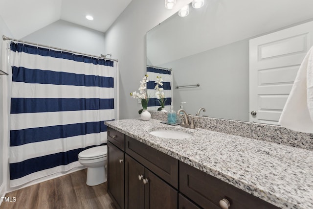 bathroom featuring vanity, hardwood / wood-style flooring, toilet, and vaulted ceiling