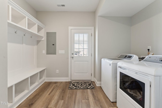 laundry room with electric panel, washer and clothes dryer, and light hardwood / wood-style floors