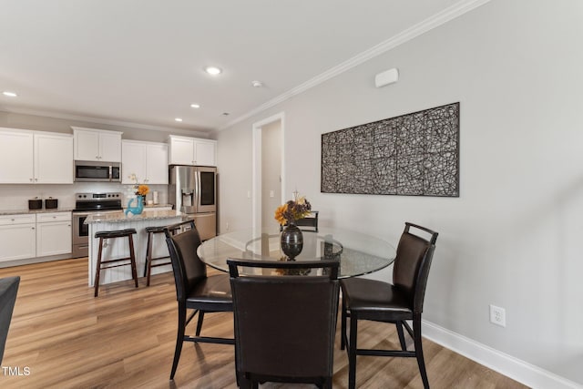 dining space featuring light hardwood / wood-style flooring and crown molding