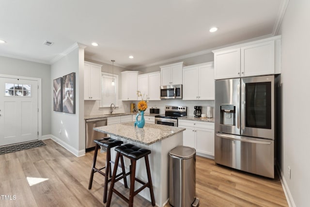 kitchen featuring appliances with stainless steel finishes, pendant lighting, white cabinetry, and a center island