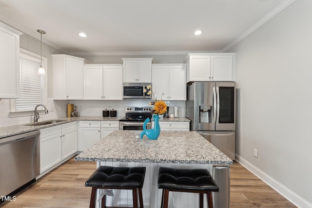 kitchen with stainless steel appliances, a center island, pendant lighting, sink, and light hardwood / wood-style flooring