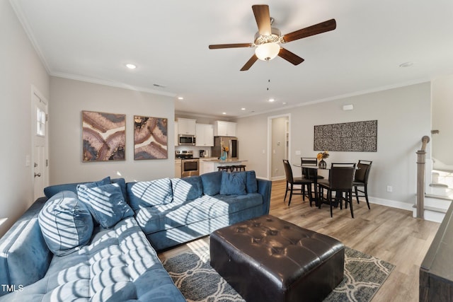 living room with crown molding, ceiling fan, and light hardwood / wood-style flooring