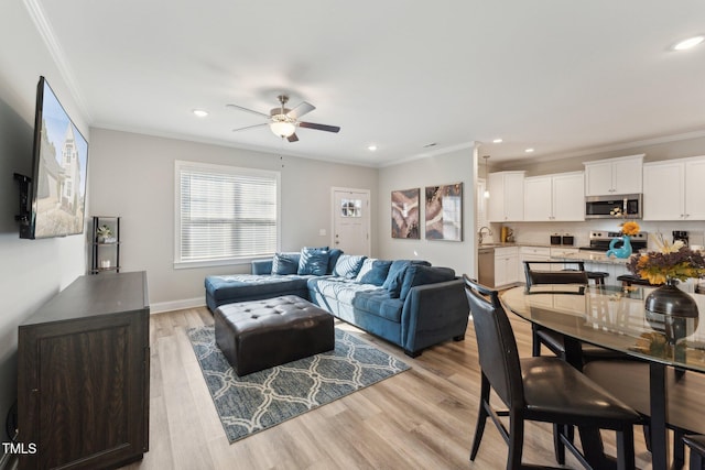 living room with light hardwood / wood-style floors, ceiling fan, and crown molding