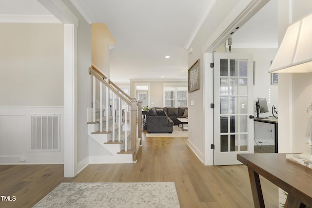 foyer entrance with crown molding and light hardwood / wood-style flooring