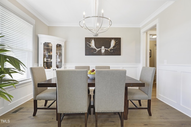 dining area with dark wood-type flooring, an inviting chandelier, and crown molding