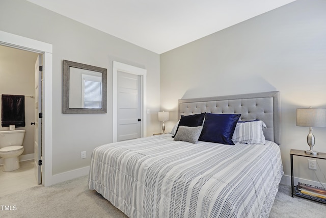 bedroom with ensuite bathroom and light carpet