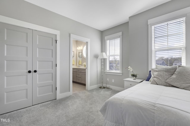 carpeted bedroom with ensuite bathroom and a closet