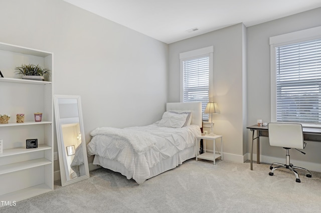 bedroom with multiple windows and light colored carpet