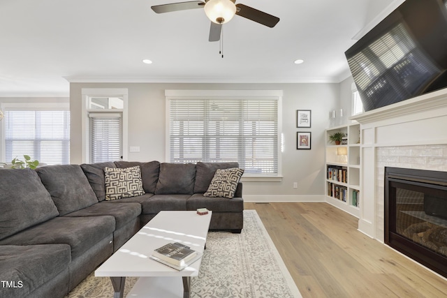 living room featuring light wood-type flooring, crown molding, ceiling fan, and a healthy amount of sunlight