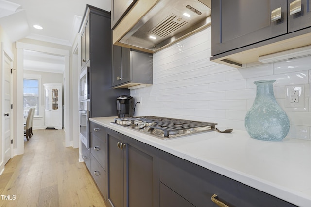 kitchen featuring premium range hood, white microwave, tasteful backsplash, light hardwood / wood-style floors, and stainless steel gas cooktop