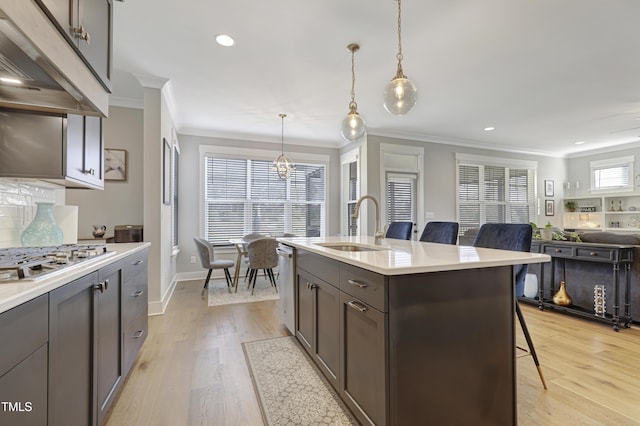 kitchen featuring a kitchen island with sink, hanging light fixtures, sink, appliances with stainless steel finishes, and a breakfast bar area