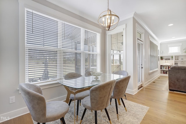 dining room with light wood-type flooring, an inviting chandelier, and crown molding