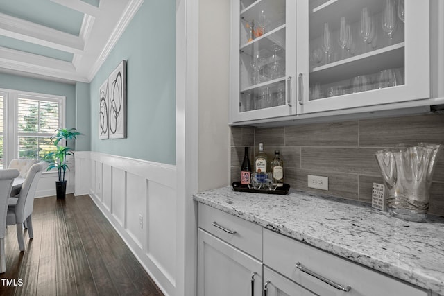 bar with dark wood-type flooring, white cabinets, crown molding, decorative backsplash, and light stone counters