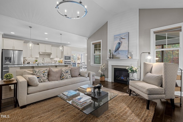 181 Colonial Ridge Dr, Pittsboro, NC 27312 - living room featuring wood finished floors, vaulted ceiling, a chandelier, baseboards, and a glass covered fireplace