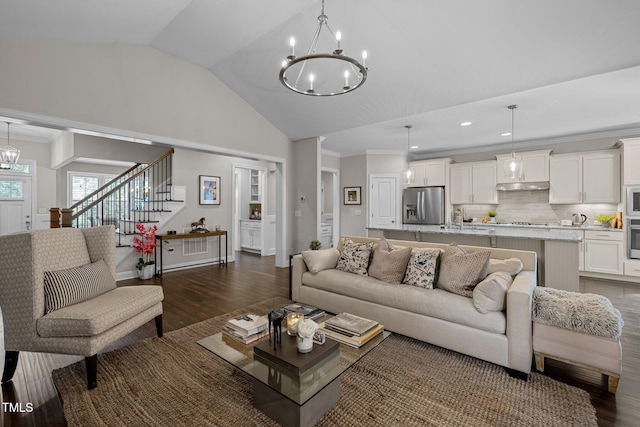 living room featuring a notable chandelier, dark wood-type flooring, lofted ceiling, and ornamental molding