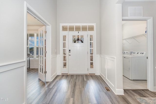 foyer with washing machine and clothes dryer and light hardwood / wood-style flooring