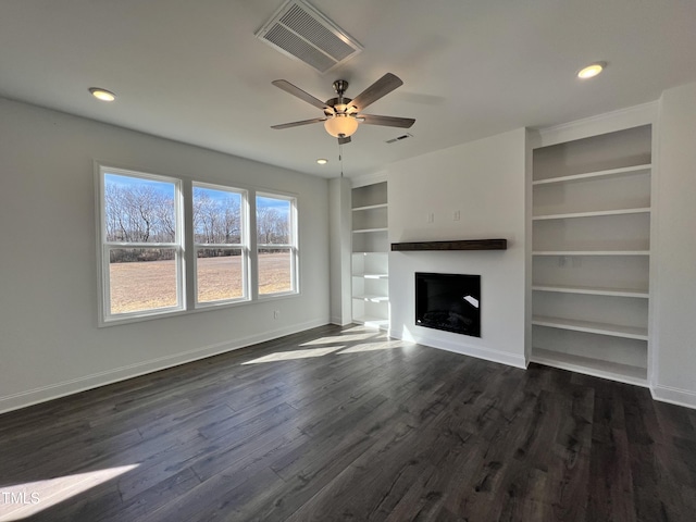 unfurnished living room with built in shelves, ceiling fan, and dark hardwood / wood-style floors