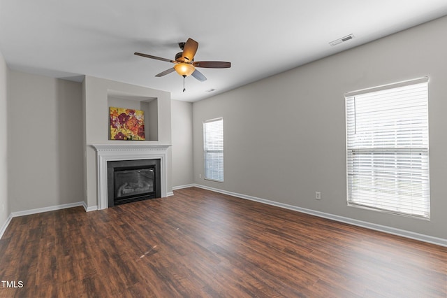 unfurnished living room featuring ceiling fan, a healthy amount of sunlight, and dark hardwood / wood-style floors