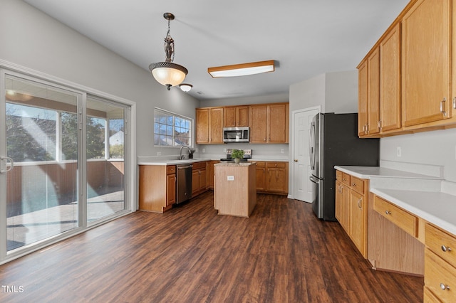 kitchen featuring sink, dark hardwood / wood-style flooring, decorative light fixtures, a kitchen island, and appliances with stainless steel finishes