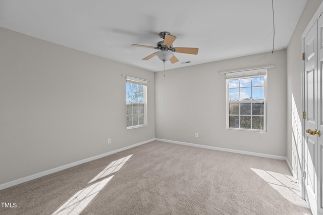 empty room featuring ceiling fan, light colored carpet, and a healthy amount of sunlight