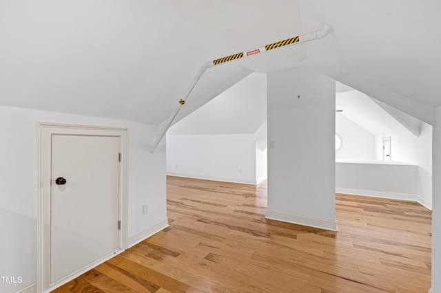 additional living space featuring lofted ceiling, light wood-style flooring, and baseboards