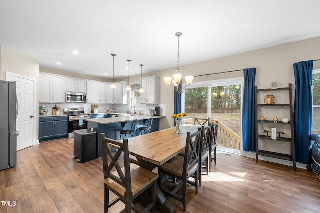 dining area with dark hardwood / wood-style floors, sink, and a notable chandelier