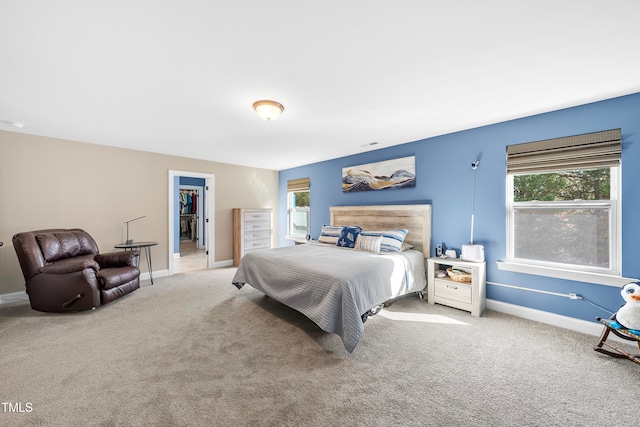 bedroom with light carpet, a closet, and a walk in closet