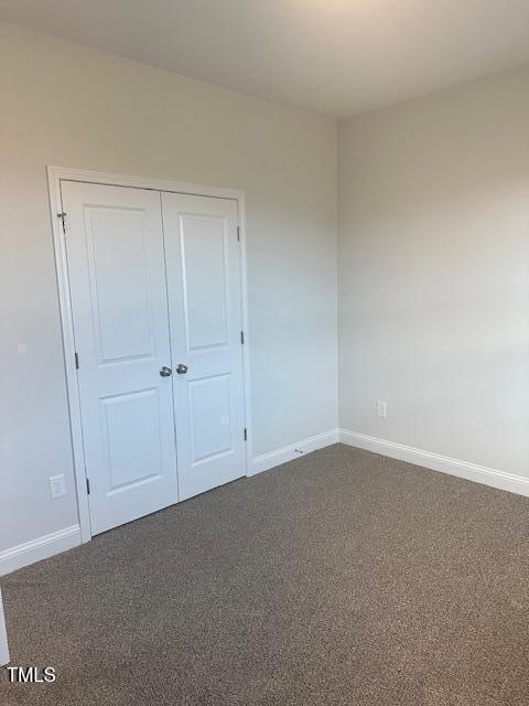 unfurnished bedroom featuring dark colored carpet and a closet