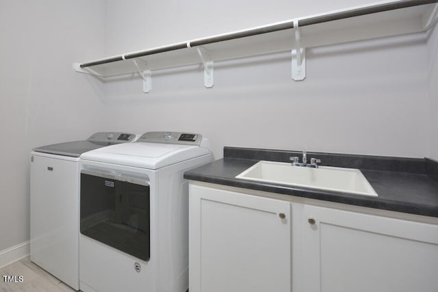 washroom with cabinets, washer and dryer, and sink