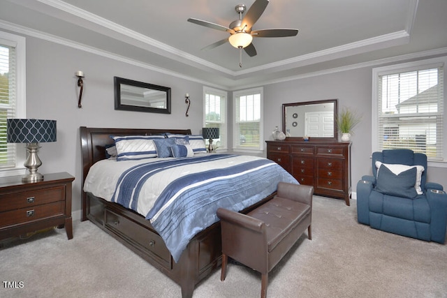 bedroom featuring ornamental molding, a tray ceiling, light carpet, and ceiling fan