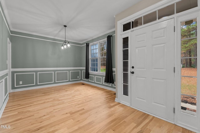 foyer featuring wood-type flooring, an inviting chandelier, and crown molding