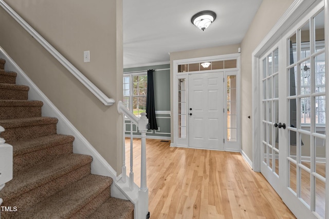 foyer entrance with french doors, light wood-type flooring, and crown molding